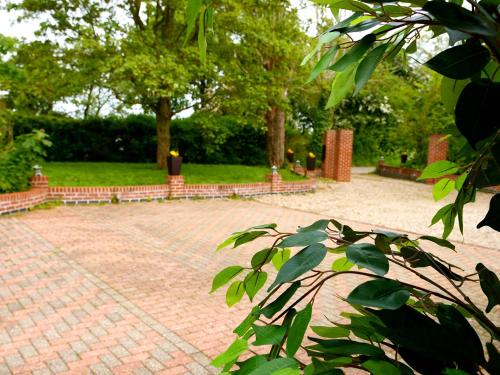 a brick courtyard with benches and trees in a park at Deluxe 4 5 Bed Hot Tub Cinema Room 15 in Saffron Walden