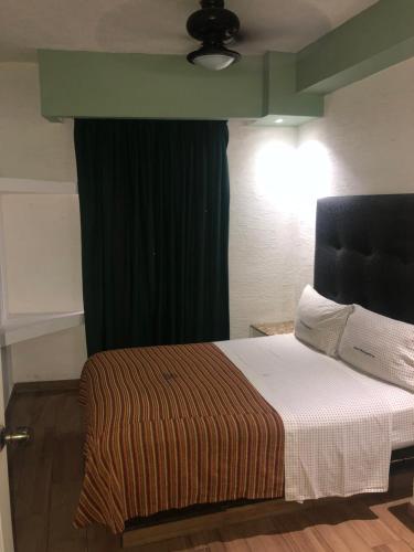 Hotel Metropolitan في غواذالاخارا: غرفة نوم بسرير وستارة خضراء