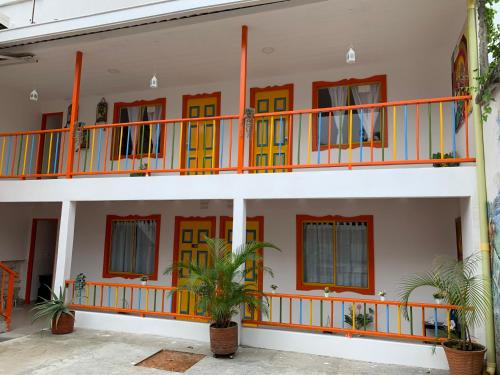 um edifício com portas laranja e amarela e uma varanda em El Rincón de Granada Hotel em Cali