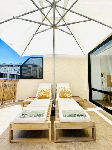 2 camas en un patio bajo una sombrilla en Caparica Rooftop Beach Apartment, en Costa da Caparica