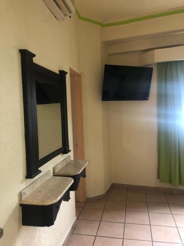 uma casa de banho com espelho e uma televisão na parede em Hotel Astur em Guadalajara