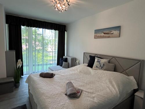 a bedroom with a large white bed with a chandelier at Villa Bauhaus Silver Wellness Apartman in Siófok