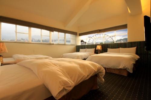 a hotel room with three beds and a window at Mountain Fish Water Hotel in Jiji