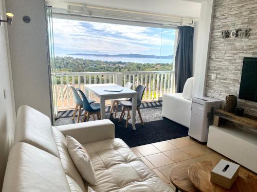 un soggiorno con divano e tavolo e un balcone di Appt Climatisé Vue Mer Club P&V Restanques Golfe de Saint-Tropez - Les Roses - Grimaud a Grimaud