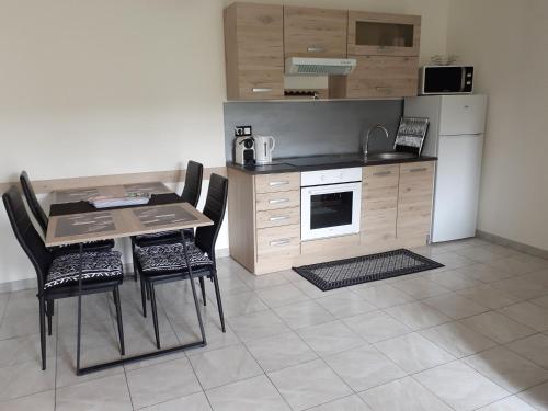 eine Küche mit einem Tisch und Stühlen sowie einem Kühlschrank in der Unterkunft SAPHIR in Nogent-sur-Oise
