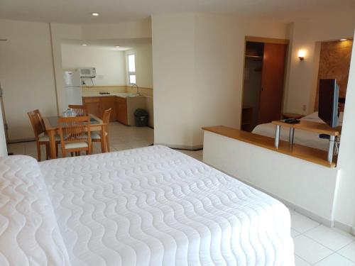 Angeles Suites & Hotel في فيراكروز: سرير أبيض كبير في غرفة مع مطبخ