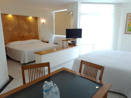 una habitación de hotel con 2 camas y una mesa con botellas de agua en Angeles Suites & Hotel, en Veracruz