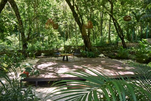 a garden with a bench and a table and trees at NATURA Loft Garden in Santa Teresa Beach