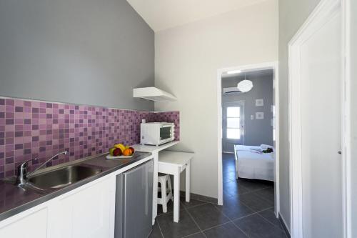 a kitchen with a sink and purple tiles on the wall at Nikolas Studios in Masouri