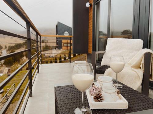 a balcony with two glasses of wine on a table at HUUT in Zlatibor