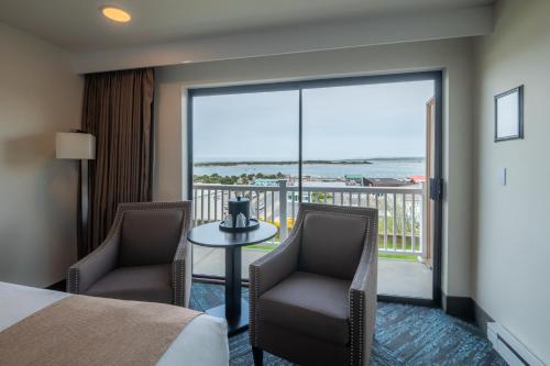 a hotel room with a bed and chairs and a balcony at Bandon Inn in Bandon