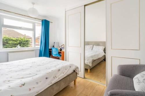 um quarto com uma cama e um espelho em Beaconsfield 4 Bedroom House in Quiet and a very Pleasant Area, Near London Luton Airport with Free Parking, Fast WiFi, Smart TV em Luton