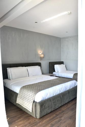 two beds in a room with white walls and wood floors at Royal G Max in Golem