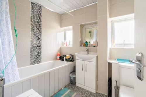 a bathroom with a tub and a sink at Beaconsfield 4 Bedroom House in Quiet and a very Pleasant Area, Near London Luton Airport with Free Parking, Fast WiFi, Smart TV in Luton