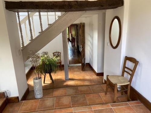 a hallway with a staircase with a chair and a mirror at La Colline aux Licornes in Montbron