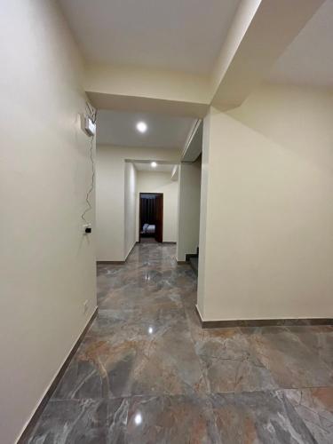 an empty hallway with a stone floor and white walls at Honey Bee in Leh