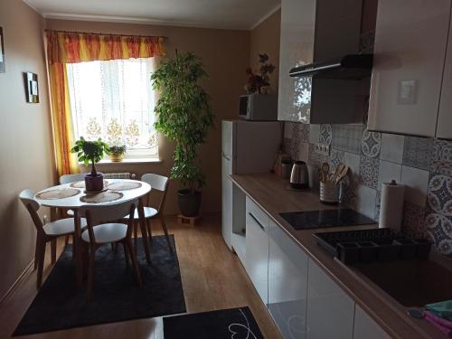 Apartament Suwalski Zakątek في سووالكي: مطبخ مع طاولة وطاولة صغيرة مع كراسي