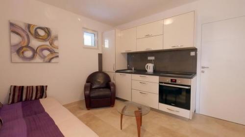 une cuisine avec des armoires blanches et une chaise et une table en verre dans l'établissement Apartment Skada, à Sveti Stefan