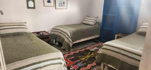Cette chambre comprend 2 lits jumeaux et une table. dans l'établissement Hotel-Restaurant Le Kaouki, à Sidi Kaouki