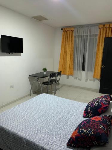 a bedroom with a bed and a table and a television at El Rincón de Granada Casa de Huespedes in Cali