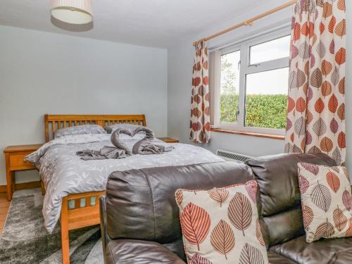 a bedroom with a bed and a couch and a window at The Pool House in Crediton