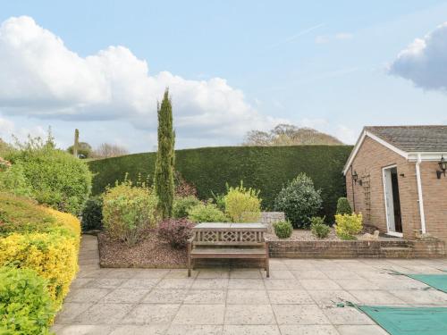 a wooden bench sitting in the middle of a garden at The Pool House in Crediton