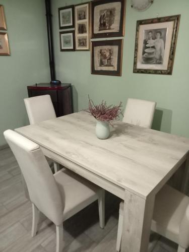a dining room table with white chairs and a vase on it at La casetta di samba in Anguillara Sabazia