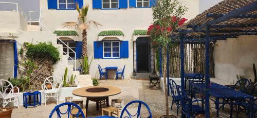 a patio with a table and chairs and a building at Hotel-Restaurant Le Kaouki in Sidi Kaouki