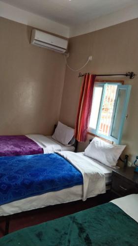 a bedroom with two beds and a window at Etoile des Gorges in Aït Baha