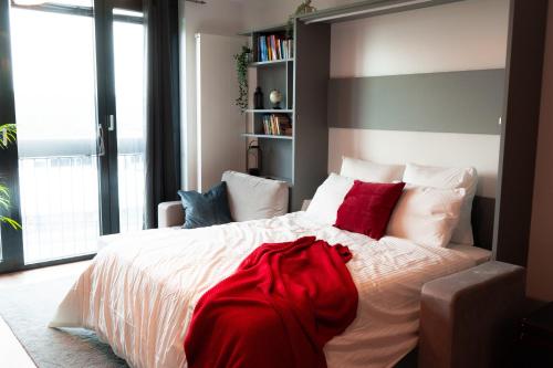 ein Schlafzimmer mit einem großen weißen Bett mit roten Kissen in der Unterkunft Industrial Apartment in Belval the University City in Esch-sur-Alzette