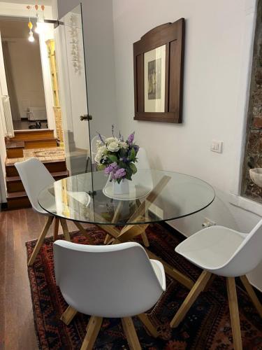 a glass table with white chairs and a vase of flowers at Golfo Dei Poeti Apartment in Lerici
