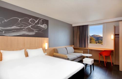 a hotel room with two beds and a chair and a window at ibis Clermont Ferrand Nord Riom in Riom