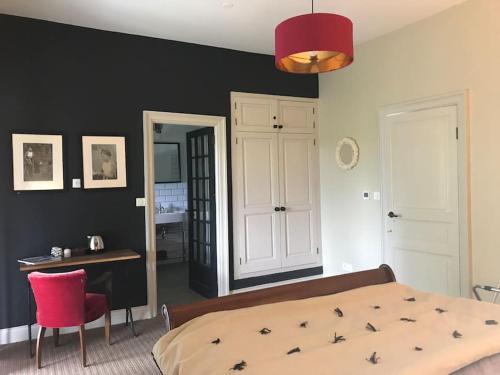 um quarto com uma cama, uma secretária e uma cadeira vermelha em Château de Bataillé em Figeac