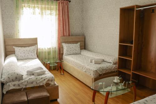 a small room with two beds and a glass table at Styopa Hotel in Yerevan