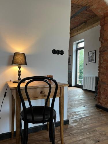 a black chair sitting at a wooden desk with a lamp at Ublik Stacja in Ublik