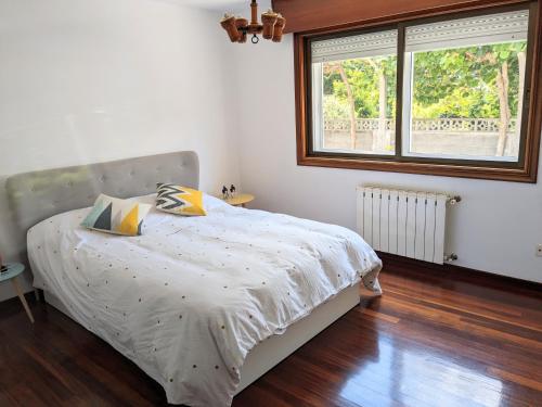 - une chambre avec un lit avec une couette blanche et 2 fenêtres dans l'établissement Bolboreta Nigrán, à Nigrán