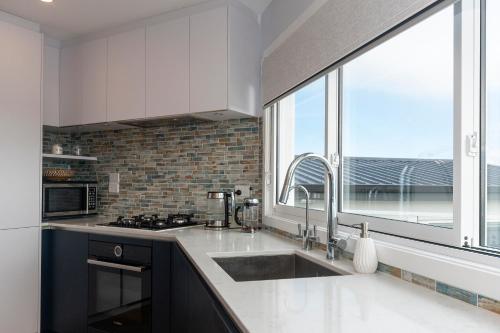 une cuisine avec un évier et une grande fenêtre dans l'établissement Luxury Lookout - Cable Bay Holiday Home, à Cable Bay