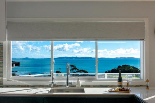 a kitchen window with a view of the ocean at Luxury Lookout - Cable Bay Holiday Home in Cable Bay