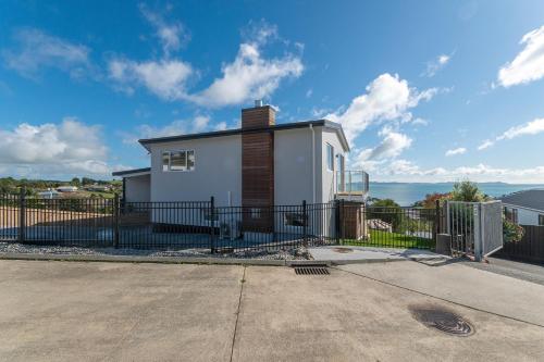 a small white house with a black fence at Luxury Lookout - Cable Bay Holiday Home in Cable Bay