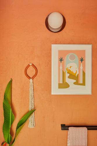 an orange wall with a picture and a towel at WALD HAUS by DW in Naguabo