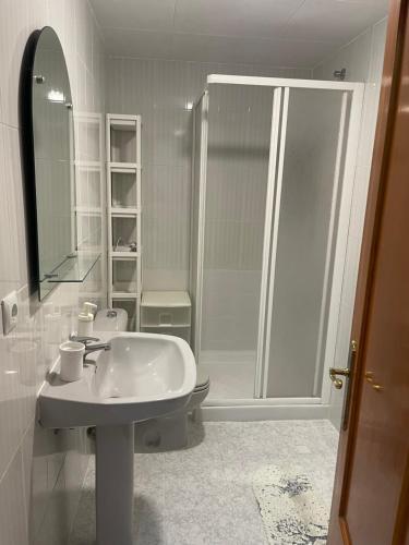 La salle de bains blanche est pourvue d'une douche et d'un lavabo. dans l'établissement Apartament Monserrat, à Torrevieja
