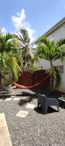 a hammock in front of a building with palm trees at Studio MADRAS AVEC PISCINE PARTAGEE A 5 MN DE LA MER in Saint-François