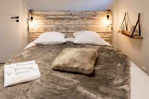 a bedroom with a large bed with a wooden headboard at "La Parenthèse" Gîte avec Jacuzzi privatif dans un jardin arboré in Roques Sur Garonne
