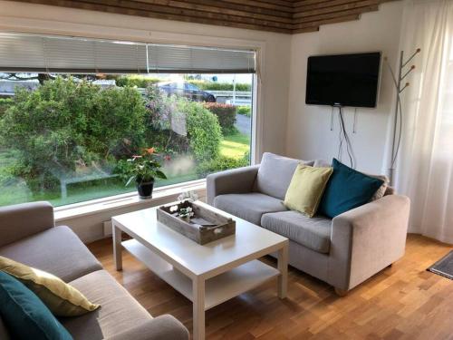 un soggiorno con 2 divani, un tavolo e una finestra di Lys og trivelig leilighet i Larvik a Larvik