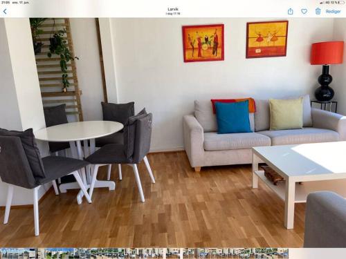 a living room with a couch and a table and chairs at Lys og trivelig leilighet i Larvik in Larvik