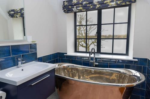 a bathroom with a tub and a sink and a window at Tarn End Cottage with view to Talkin Tarn, near Lake District in Brampton