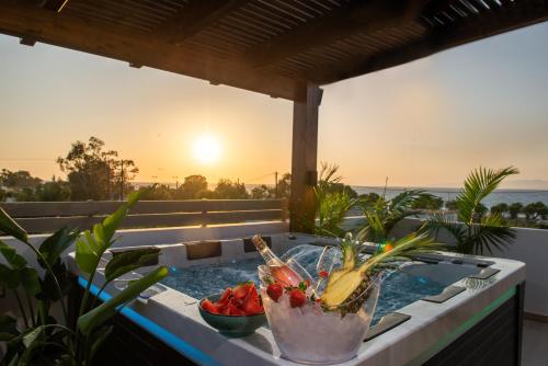 uma banheira de hidromassagem com frutas numa varanda com o pôr-do-sol em ODYSSEA Top View & Hot Jacuzzi Front Beach em Kremasti
