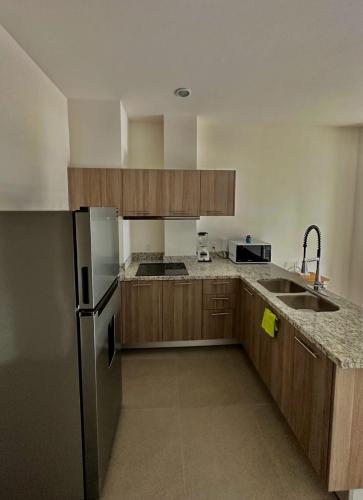a kitchen with wooden cabinets and a stainless steel refrigerator at Departamento en Mazatlán Torre Zuñiga in Mazatlán