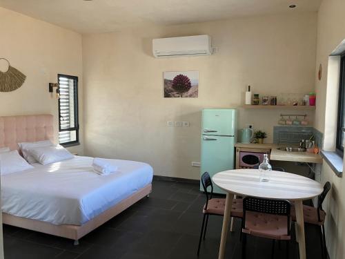 1 dormitorio con cama, mesa y cocina en בסנדלים: חאן בוטיק בגולן en Ma'ale Gamla