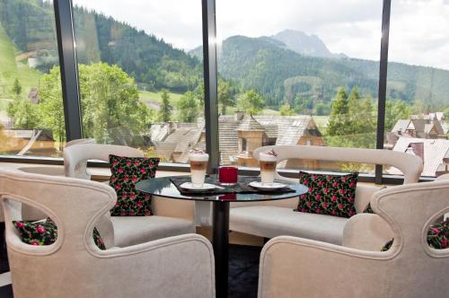 a room with a table and chairs and a large window at Grand Nosalowy Dwór in Zakopane